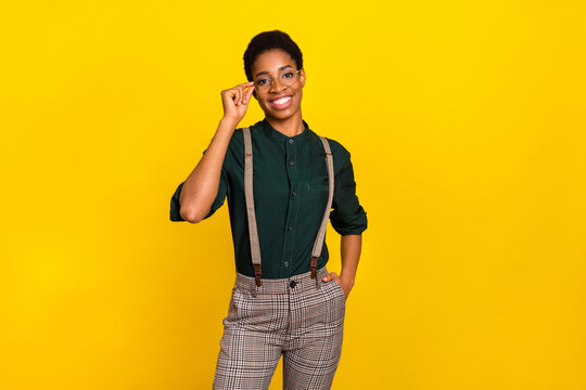 Portrait of attractive cheerful intellectual woman touching specs posing isolated over bright yellow color background
