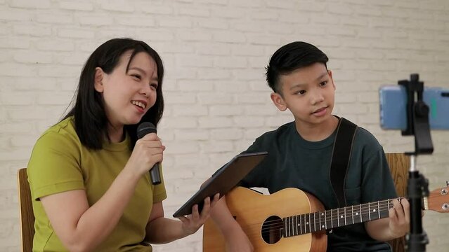 Mother and son sang and played music together and recorded videos on their smartphones. Online music concept. Online music performances. Family relationship activities