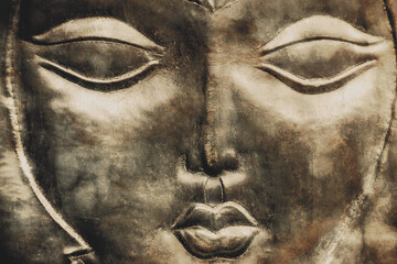 A woman's face, a mask embossed on metal.