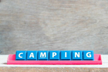 Tile alphabet letter with word camping in red color rack on wood background