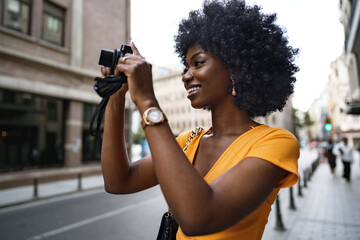 Smiling African american woman using professional camera at a street