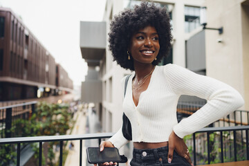 Portrait of young african woman with afro hairstyle standing at balcony and posing.