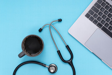 black stethoscope, laptop, coffee, blue isolated background