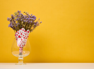 Dry bouquet of wild flowers in a vase on a yellow background