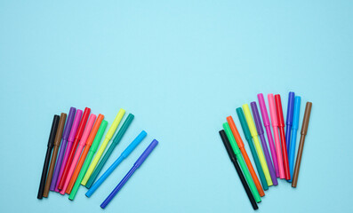 Fototapeta premium Stack of multicolored felt-tip pens on a blue background