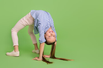 Photo of positive energetic kid girl wear striped shirt make bridge pose stretch spine isolated...