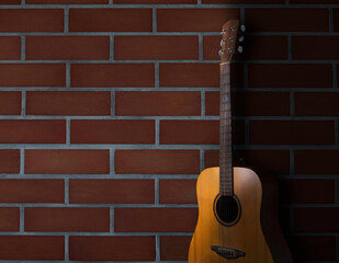 acoustic guitar stand in front of brick wall background. body part front made with top solid, side and back mahogany wood.