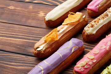 Assortment of sweet and colorful eclairs on wooden background