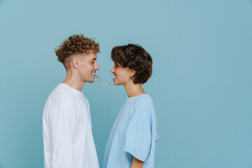 Young beautiful smiling couple eating rainbow candy together