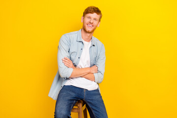Fototapeta premium Photo of attractive sweet guy dressed denim shirt hands folded sitting chair empty space isolated yellow color background