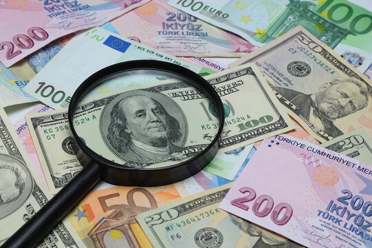 Banknotes spread out on a table with a calculator and a magnifying glass.