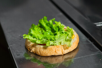 close-up of the beginning of the preparation of a colombian hamburger, in a fast food stand located on the street. bread and lettuce on a metal table. food concept.