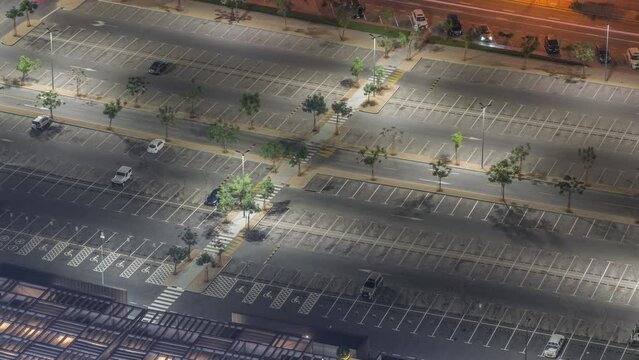 Big parking lot near mall crowded by many cars timelapse aerial view. Vehicles moves in and out during all night and bocome empty