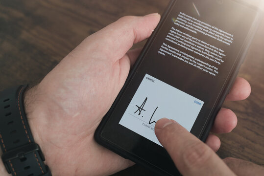 close-up view of electronic signature with finger on smartphone touchscreen against wooden table background