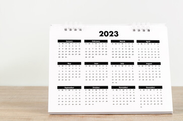 The 12 months desk calendar 2023 on wooden background.