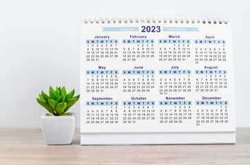 The 12 months desk calendar 2023 on wooden background.