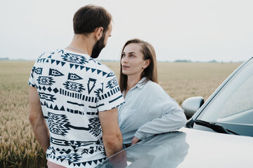 Caucasian woman and man having conversation outdoors near the car in the field, middle-aged couple on a road trip