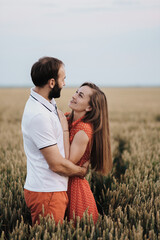 Happy middle-aged couple hugging in the wheat field, caucasian cheerful woman and man in love standing together outdoors