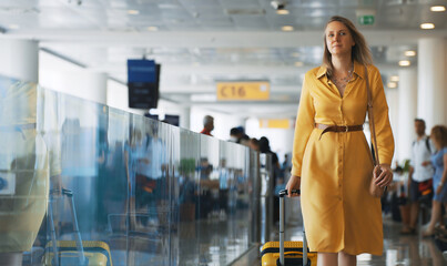 Woman with suitcase walking in airport terminal.
