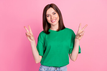 Photo portrait of pretty young woman show double v-sign hello toothy smile dressed trendy green clothes isolated on pink color background