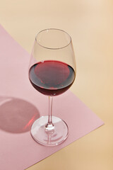Minimal concept with glass of red wine. Creative holiday idea on pastel pink background.