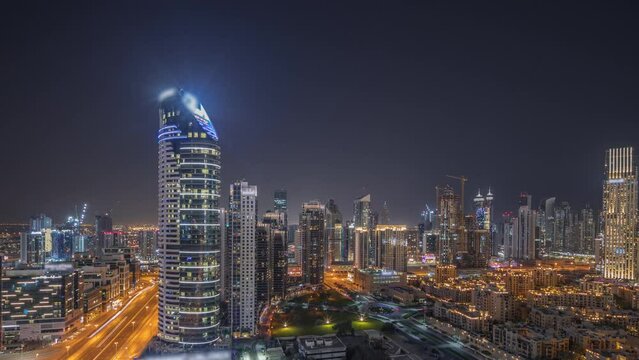 Panorama showing Dubai's business bay and downtown towers with old town aerial night timelapse. Rooftop view of some skyscrapers and new towers under construction
