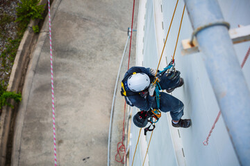Top view male worker inspection wearing safety first harness rope safety line working at a high place on tank roof spherical