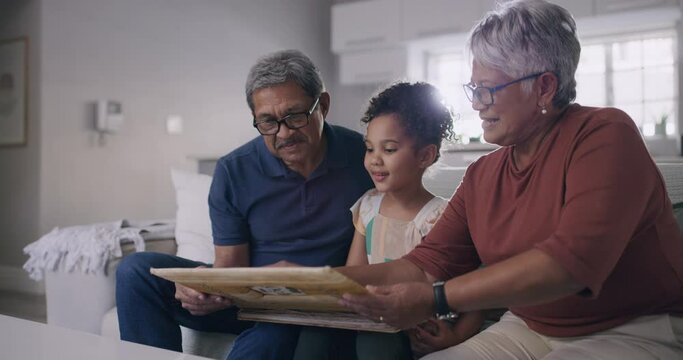 Grandparents and granddaughter looking at photos, pictures and memories while sitting at home during a visit. Senior couple and their granddaughter spending time together and bonding as a family
