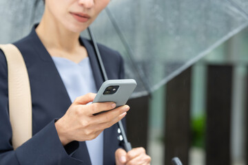 女性・雨・傘・スマートフォン