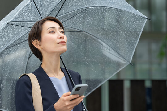 女性・雨・傘・スマートフォン