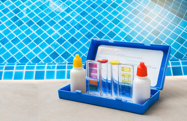 Water testing test kit for swimming pool water over blue tile background, pool water tester kit for...