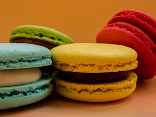 Close-up of French dessert for coffee. Multicolored macarons or macaroons on orange background. High quality photo