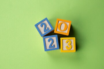 Closeup of colorful wooden blocks with numbers 2023 on a green background - New Year concept