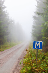 Meeting place road sign by a foggy forest road