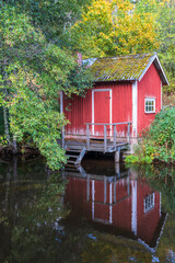 Red small cottage by the water with autumn colors
