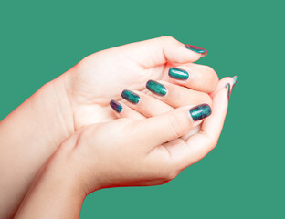 Female hand with green nail design on green background. Woman manicure is art beautiful summer style. Close-up of healthy young girl beauty fingers.