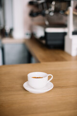 Delicious freshly brewed hot double espresso in a ceramic white cup with a saucer, standing on the bar counter of a coffee shop, vertical image