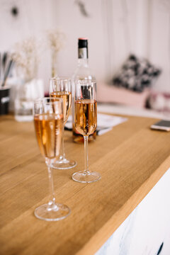 Three glasses of rose wine on the wooden bar counter with a bottle on the background, vertical photo