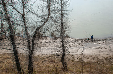 view from above the fisherman catches fish on a fishing rod and sits on a chair, fishing on the river bank in the morning. spring fishing in nature.