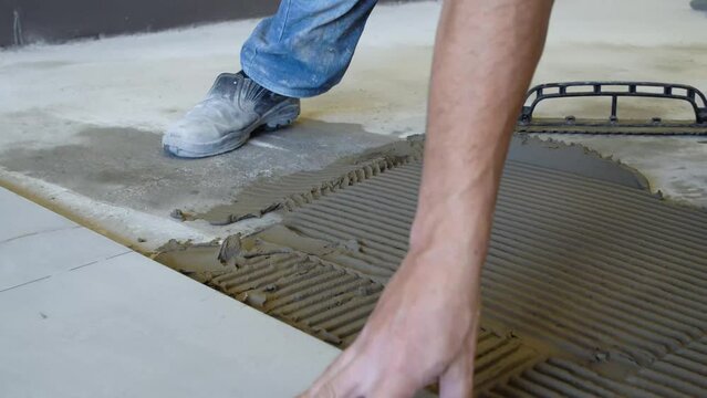 Bricklayer manually installing gray porcelain tile