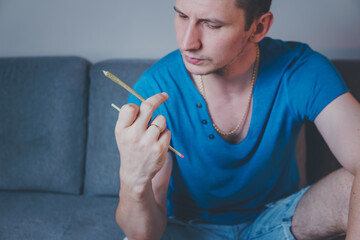 Close-up of adult man lights up with matches and smoking medical marijuana joint. Concept of herbal and alternative medicine
