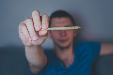 Close-up of adult man lights up with matches and smoking medical marijuana joint. Concept of herbal...
