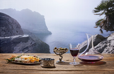 Glass and decanter filled with delicious mature red wine on wooden table isolated over mountain...