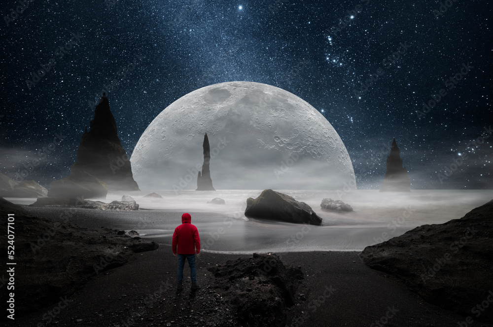 Wall mural man observing a huge moon from a beach