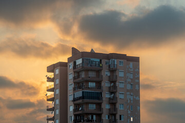 Orange sky at sunset, a high-rise building and the sun behind them, Clouds.