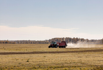 Fototapeta premium tractor spreads chemical fertilizer on the field in autumn