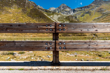 Fototapeta na wymiar Front view of wooden fence to protect the road in alpine landscape. Spluga Pass