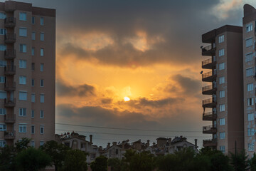 Orange sky at sunset and the sun in the middle of two tall buildings,