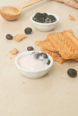 Obraz na płótnie Canvas Yogurt with berries, cookies, white dishes, wood spoon on a kitchen top 
