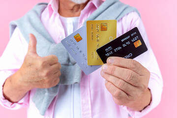 retired asian elderly man with hat broken arm wear arm splint for treatment and smiling and holding credit card for confident lifestyle.